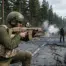 A DayZ survivor kneeling on a cracked asphalt road in Chernarus, firing the new tan SCR17 modular rifle system introduced in the 1.29 Experimental update with bullet casings flying.